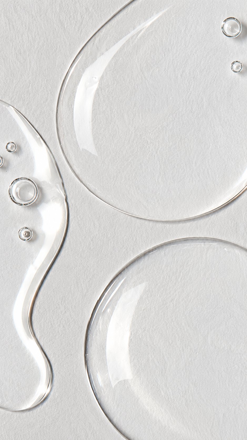 Clear, glassy serum droplets on textured paper